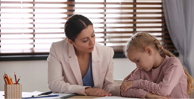 School counselor working one-on-one with young student at desk