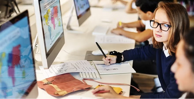 School-age girl with glasses working on computer with colorful charts and data visualization projects in classroom