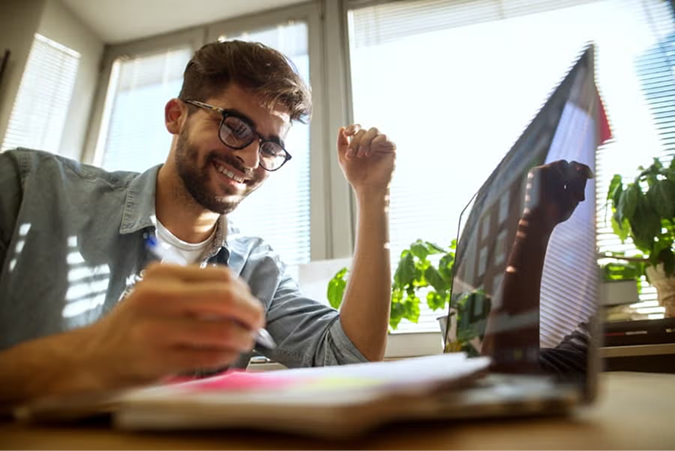 Student celebrating success with raised fist while studying