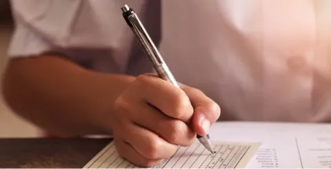 Close-up of hand writing on paper with pen